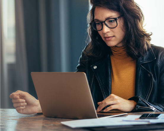 Woman wearing black glasses looking at a laptop
